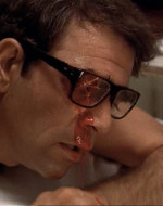 MOE puts on his glasses to see who it is and is shot through the eye. Blood gushes out.