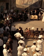 EXT DAY: VITELLI VILLAGE SQUARE. MICHAEL and APOLLONIA around the wide circle of guests.
